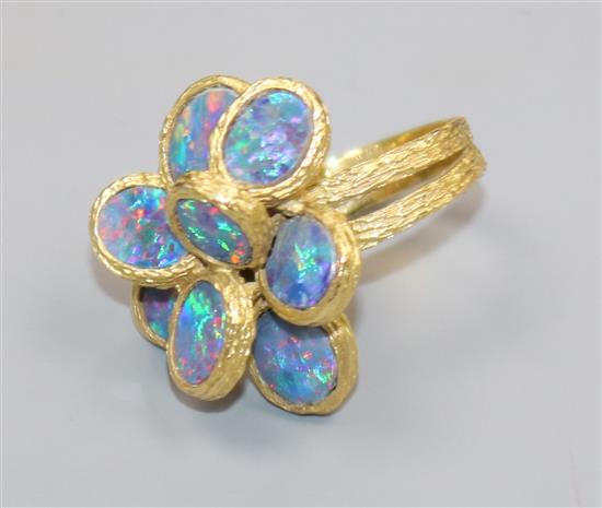 A 1970s textured 18ct gold and eight stone oval black opal set dress ring, size K/L.